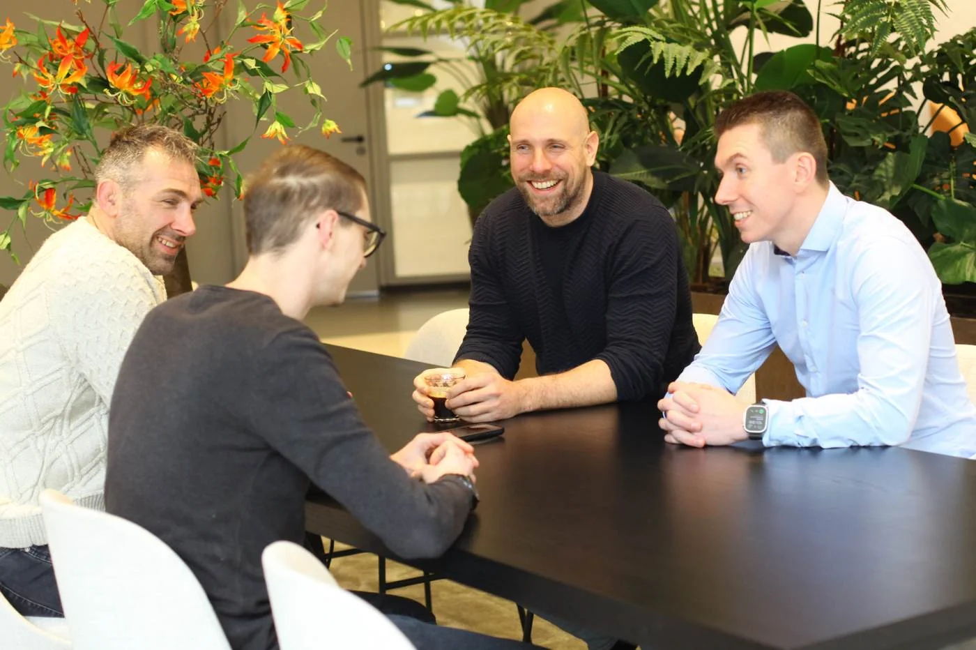 Het team van DACON in gesprek aan tafel, met koffie
