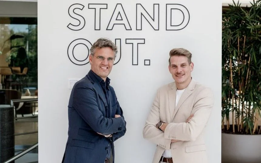 Twee DACON-collega&rsquo;s bij de STAND OUT-wand op kantoor